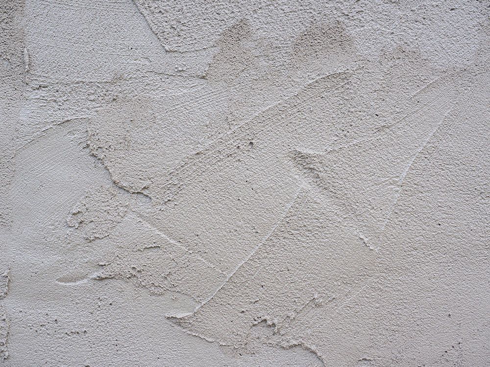 Strukturierte, hellgraue Stuckwand mit sichtbaren Kellenspuren.