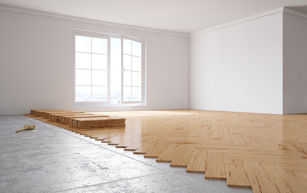 Plancher en bois partiellement installé dans une pièce lumineuse et vide aux murs et fenêtres blancs
