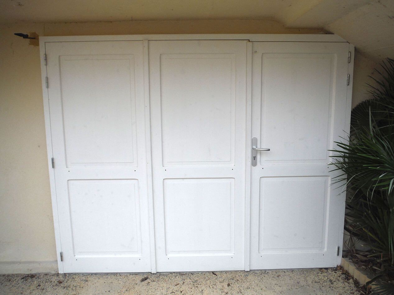 Armoire ou penderie blanche à trois portes avec une petite poignée, adossée à un mur beige à l'extérieur.