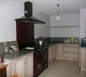 Cuisine moderne avec placards en bois clair, cuisinière noire, plans de travail gris et sol carrelé
