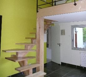 Chambre moderne avec escalier en bois suspendu, mur vert citron et sol carrelé