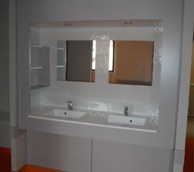 Meuble-lavabo moderne avec double vasque, grand miroir et armoires blanches.