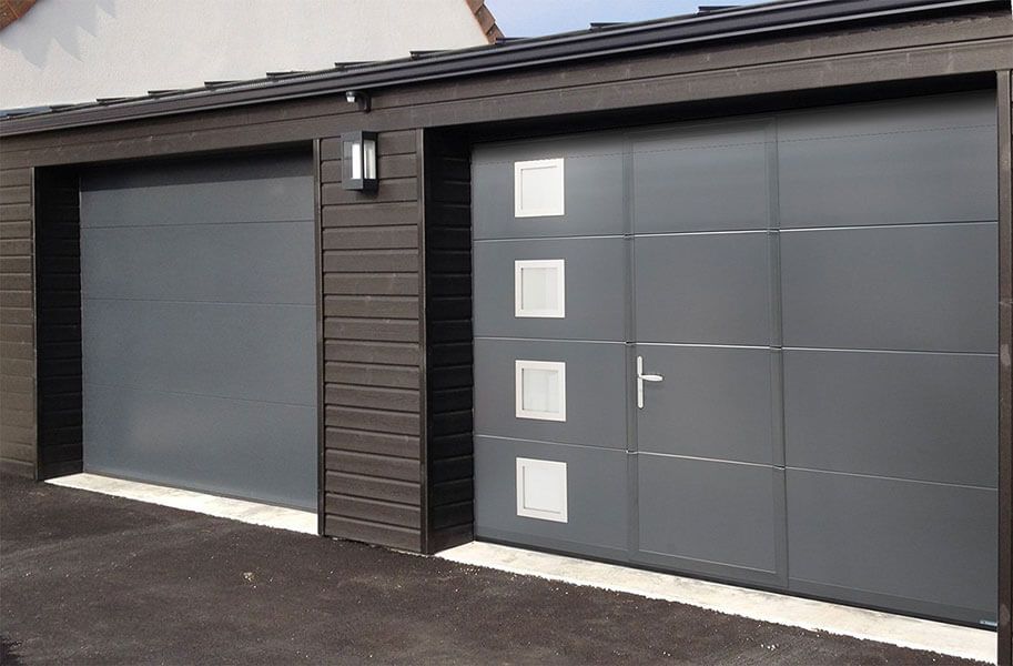 Extérieur de maison moderne avec portes de garage gris foncé et porte d'entrée à encadrement blanc