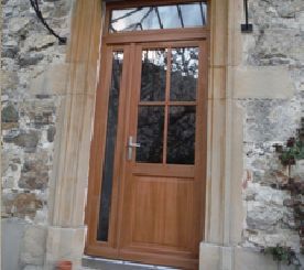 Porte vitrée en bois encastrée dans un mur en pierre, surmontée d'une imposte.