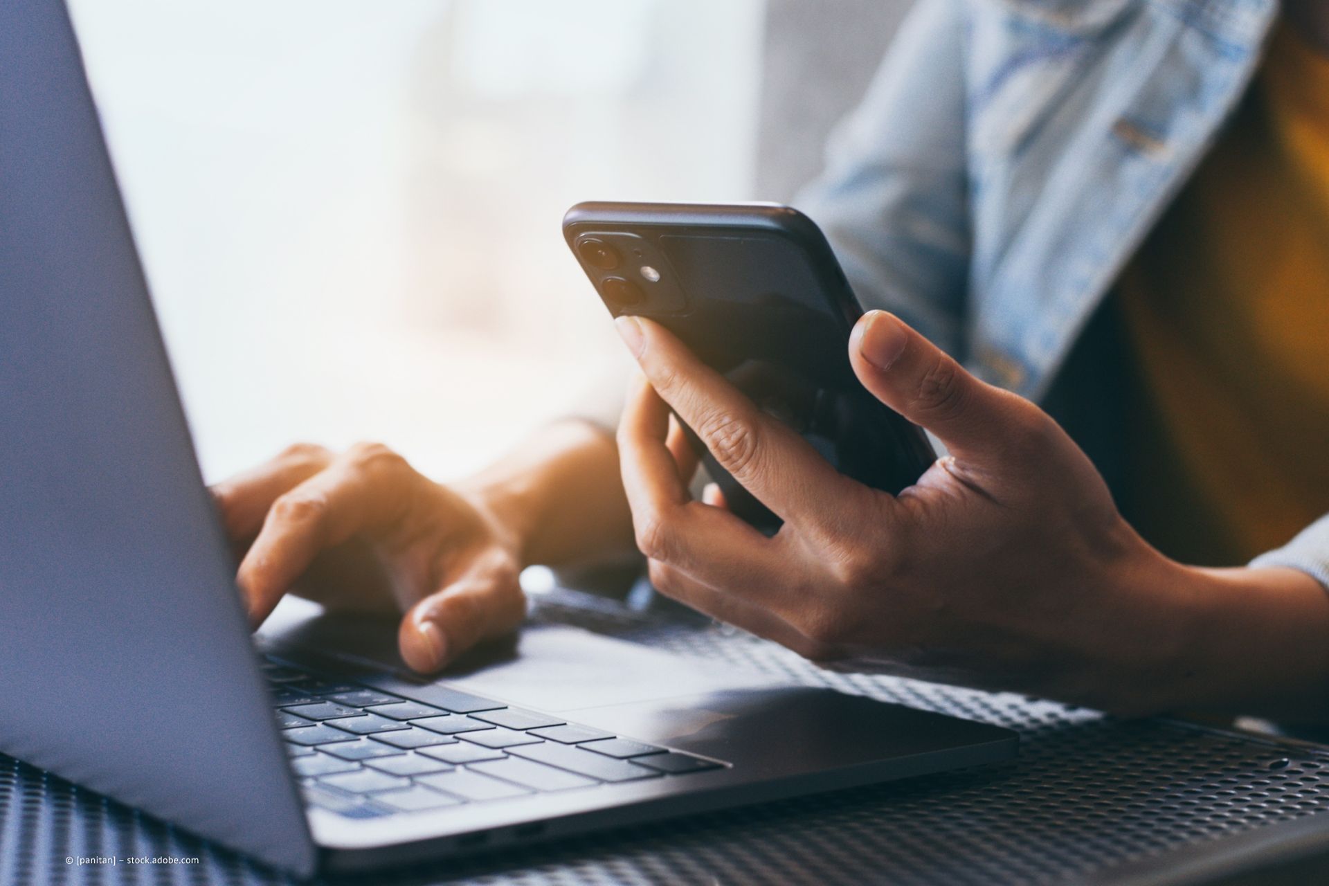 Person mit Smartphone und Laptop