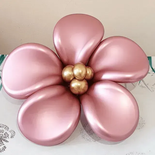 Una flor rosa hecha de globos está sobre una mesa.
