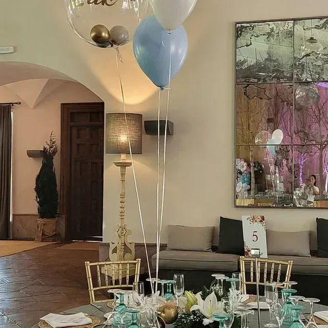 Una habitación con una mesa y sillas y globos colgando del techo.