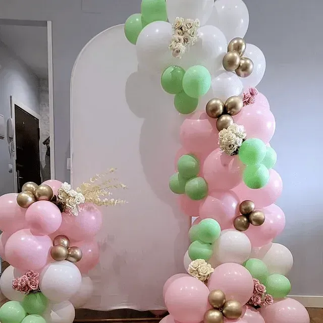 Un montón de globos rosados, verdes y blancos están colocados uno encima del otro en una habitación.