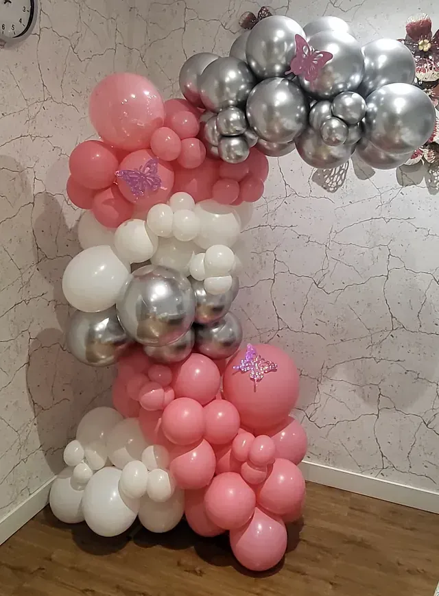 Una habitación llena de globos rosas, blancos y plateados.