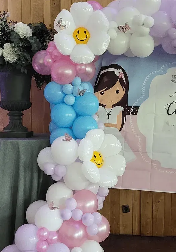 Un arco de globos con flores y una cara sonriente.