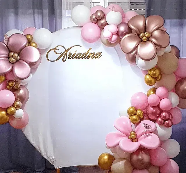 Una pared blanca está decorada con globos y flores rosas y doradas.