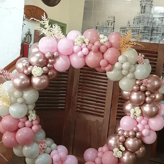 Un montón de globos rosados ​​y dorados están sobre una puerta de madera.