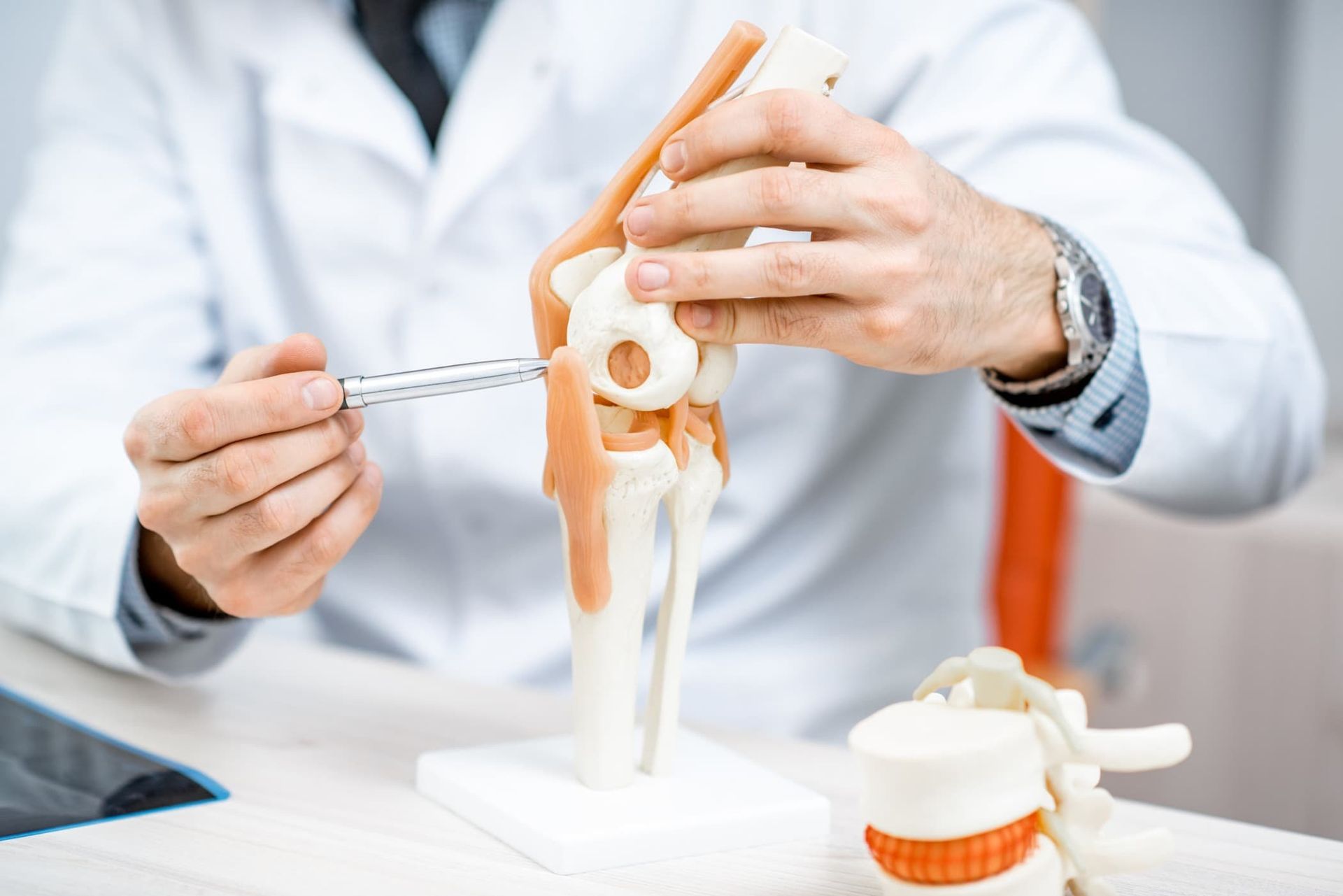 Un médico sostiene una jeringa y un modelo de una rodilla.