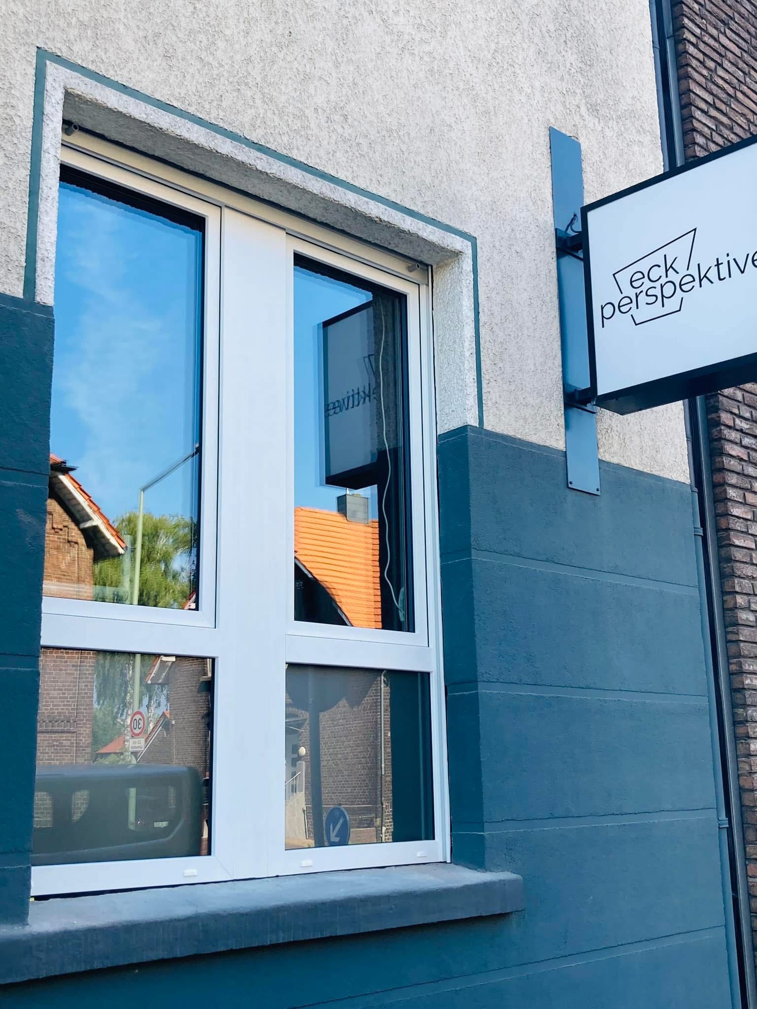 Ein Fenster an der Seite eines Gebäudes mit einem Schild darüber.