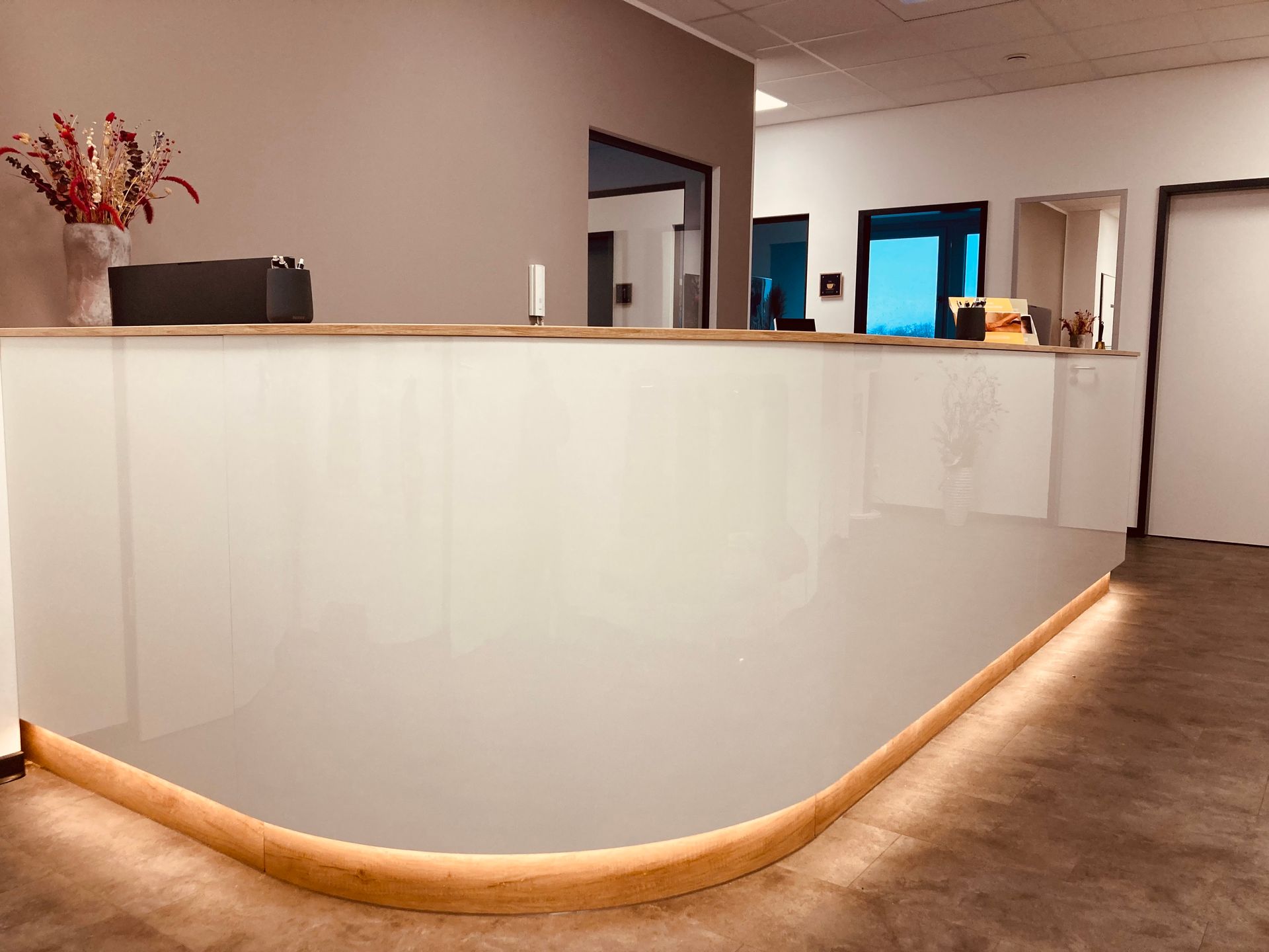 Ein weißer Rezeptionstresen in einem Raum mit einer Vase mit Blumen darauf.