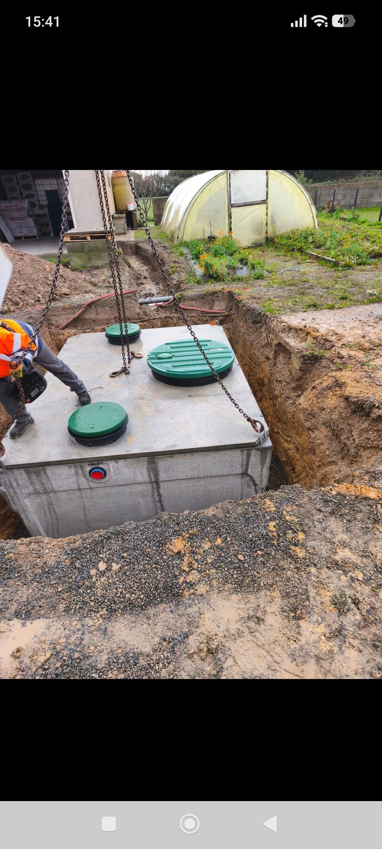 Tranchée avec conduits rouges, boîte électrique et petite pelle mécanique. Chantier par une journée ensoleillée.