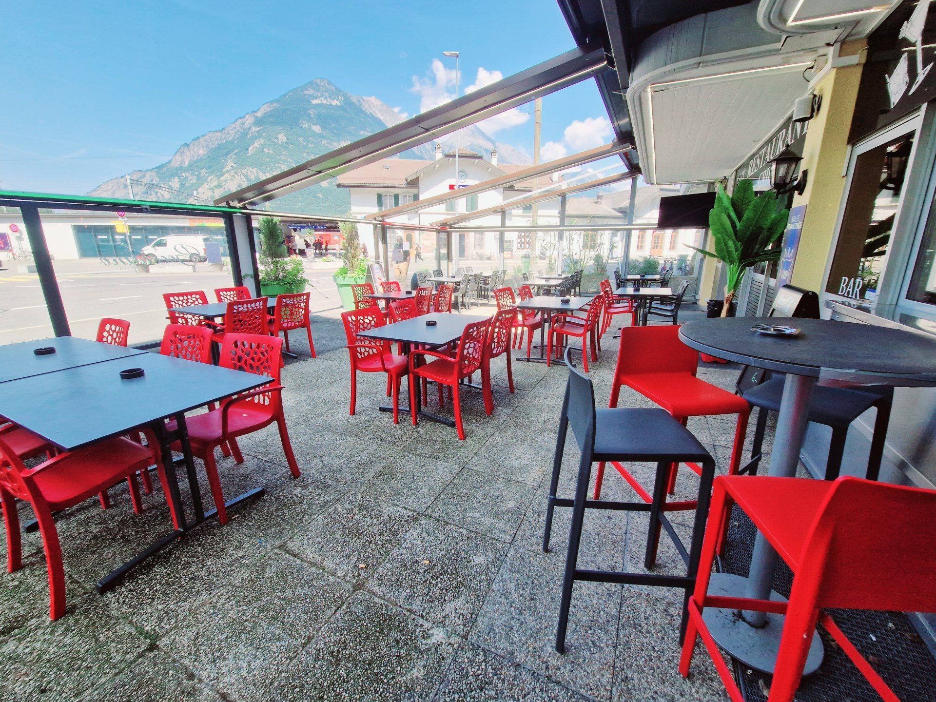 Un restaurant avec des tables et des chaises à l'extérieur avec des montagnes en arrière-plan.