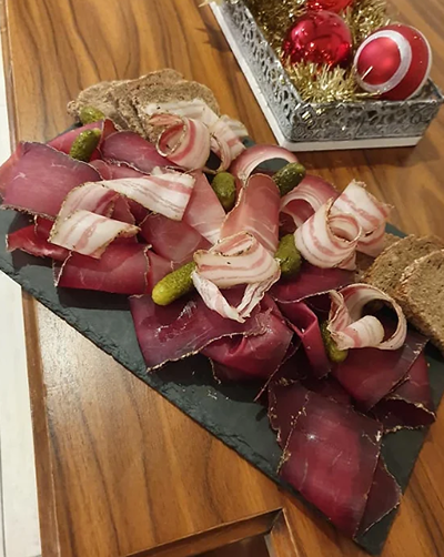 Un plateau de viande et de cornichons est posé sur une table en bois.