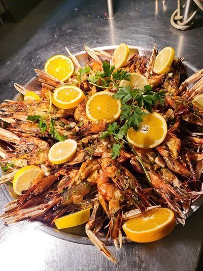 Une assiette de crevettes avec des tranches de citron et du persil sur une table.