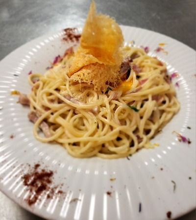 Une assiette de spaghetti avec un morceau de fromage dessus