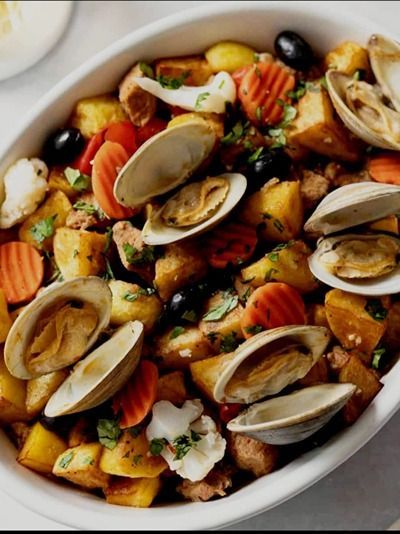 Un bol blanc rempli de palourdes et de pommes de terre