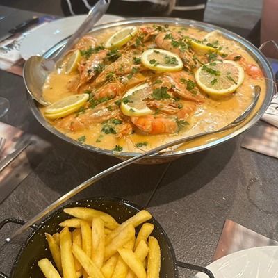 Un bol de ragoût de crevettes à côté d'un bol de frites sur une table.