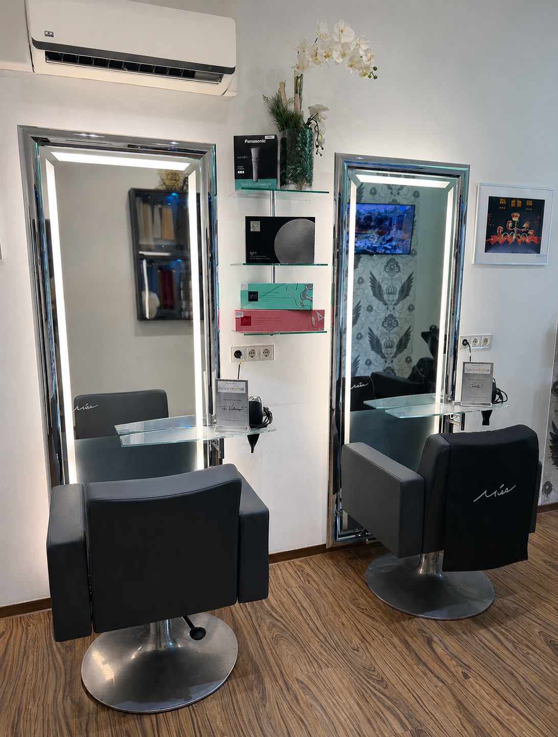 Moderner Salon mit zwei Friseurstühlen und Spiegelplätzen an einer hellen Wand