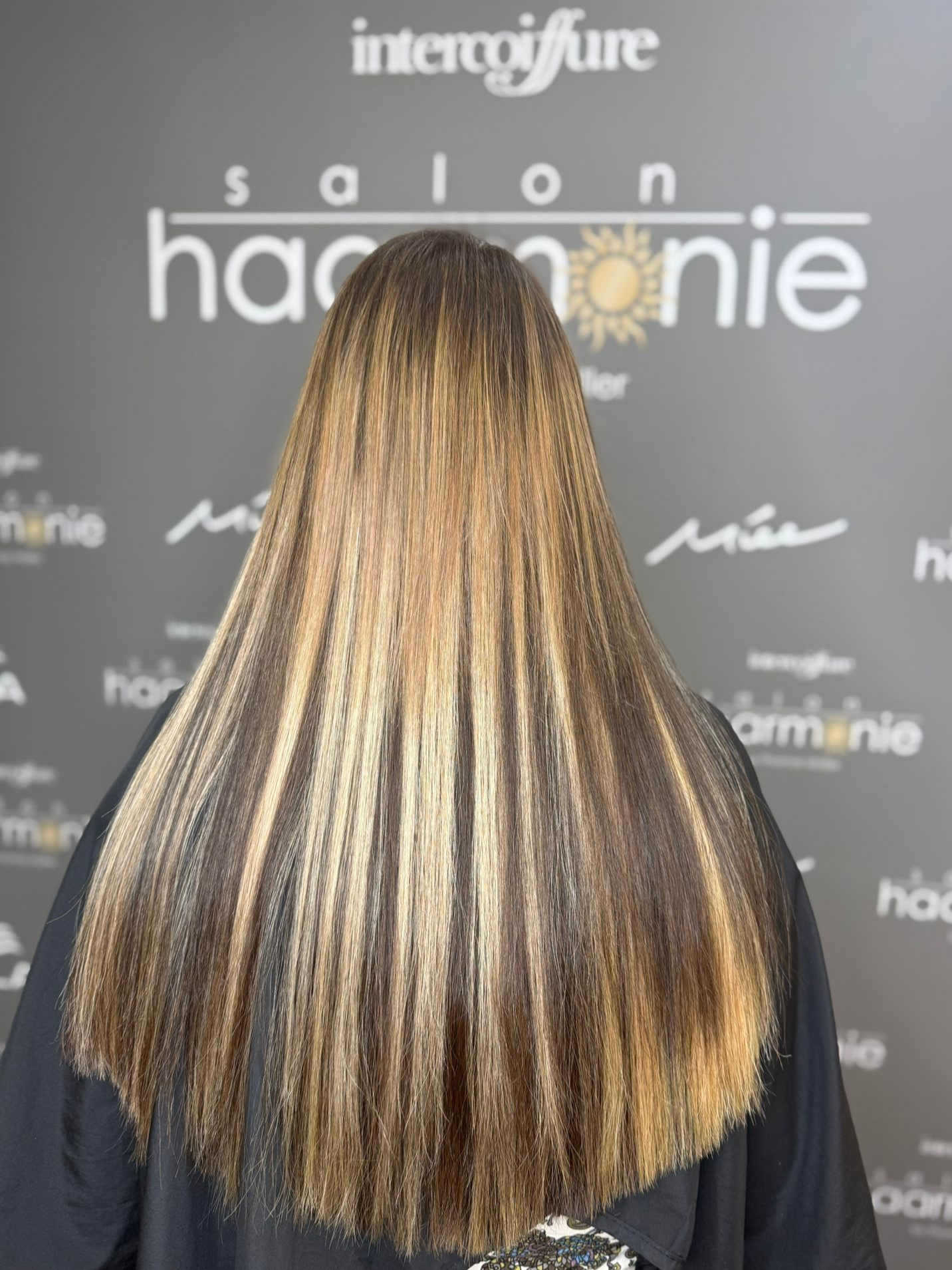 Ein Kind lässt sich im Friseursalon die Haare schneiden und lächelt, während die Schere die Haare stutzt.