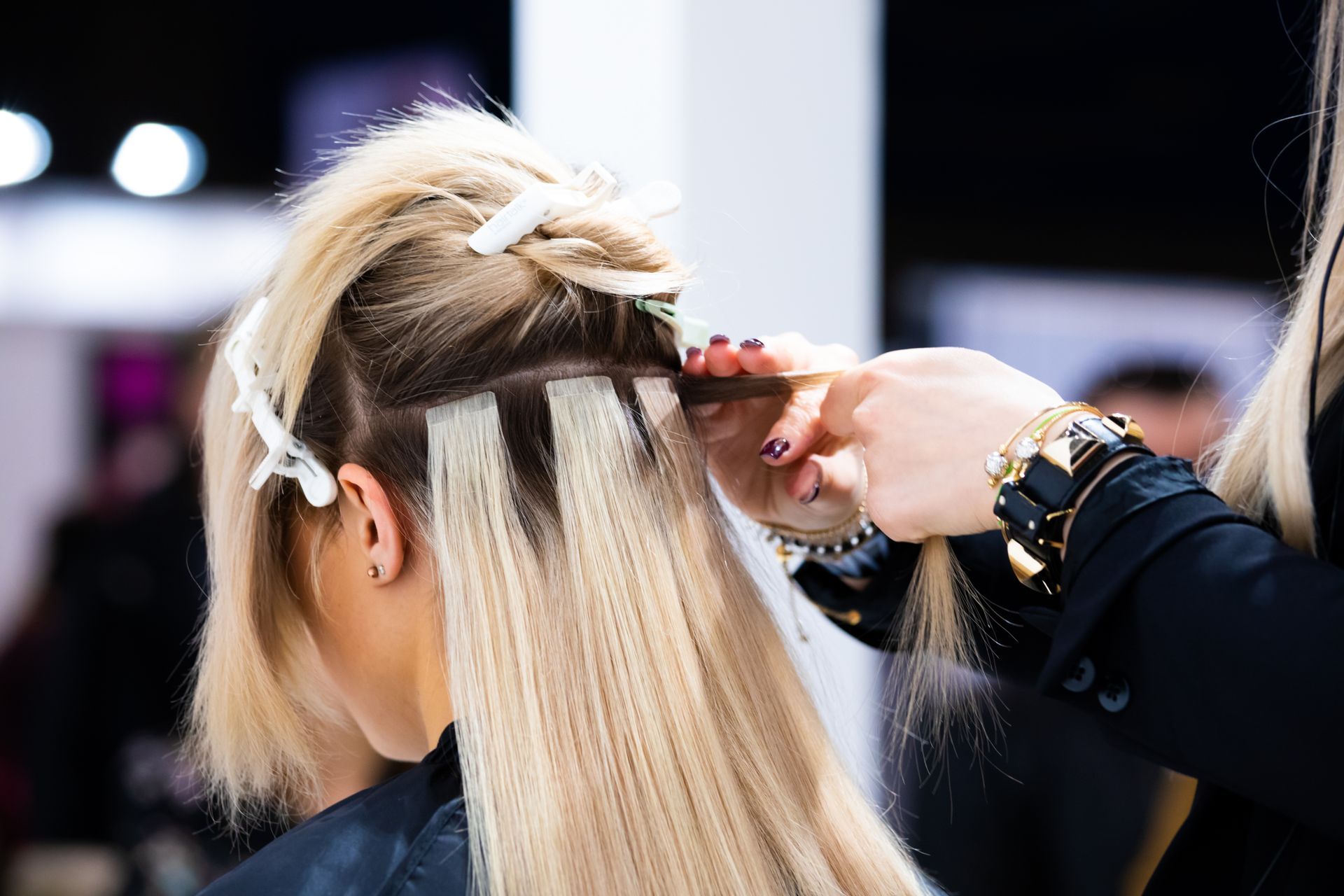 Ein Friseur stutzt einem Kunden in einem schwach beleuchteten Friseursalon mit Haarschneidemaschine und Kamm die Haare.