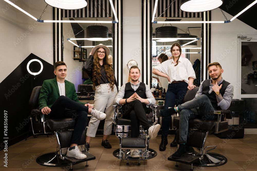Fünf Personen posierten in einem modernen Büro oder Salon, sitzend und stehend, mit Ringlicht und gestreiften Deckenleuchten.