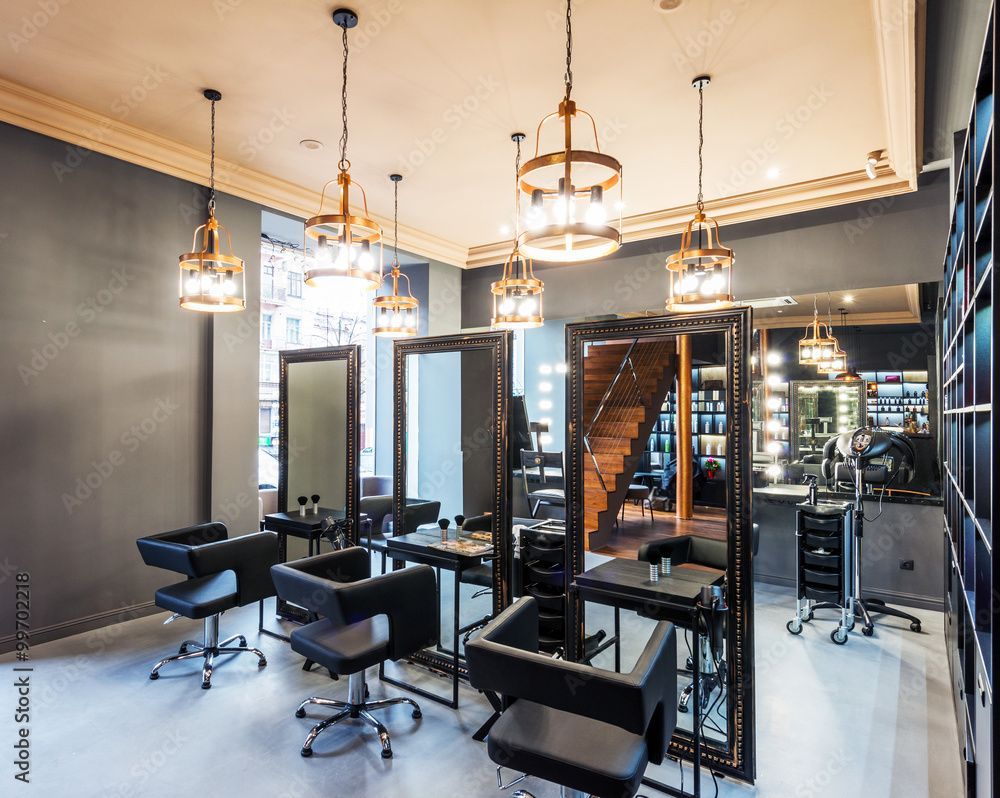Modernes Friseursalon-Interieur mit Friseurstühlen, Spiegeln, Pendelleuchten und Treppe.