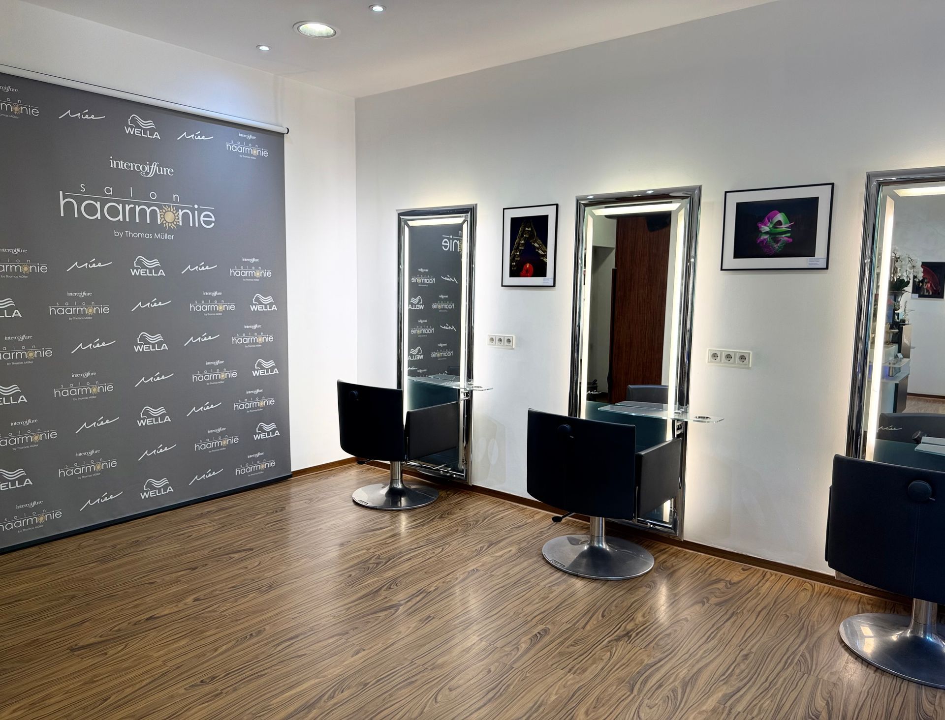 Modernes Friseursalon-Interieur mit Friseurplätzen und Spiegeln, schwarzen Stühlen und einer Wand mit Tafelfarbe