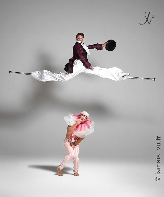 Homme en échasse qui saute par-dessus un clown