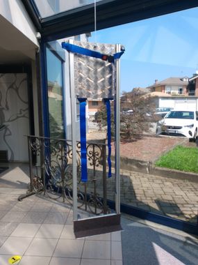 Una cinghia blu è appesa a un palo di metallo davanti a una finestra
