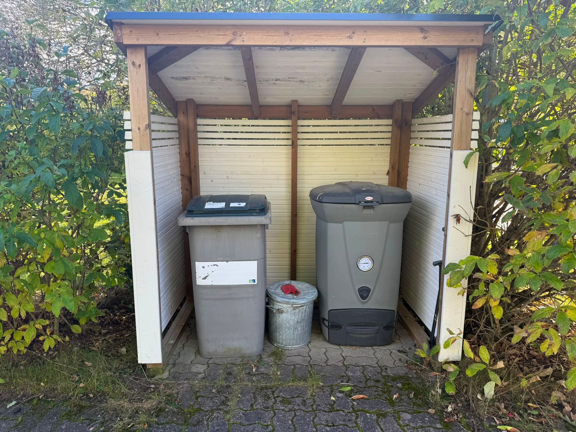 Moderni talo lasitetulla patiolla, vihreällä nurmikolla ja syksyn värisellä puulla sisäänkäynnin vieressä