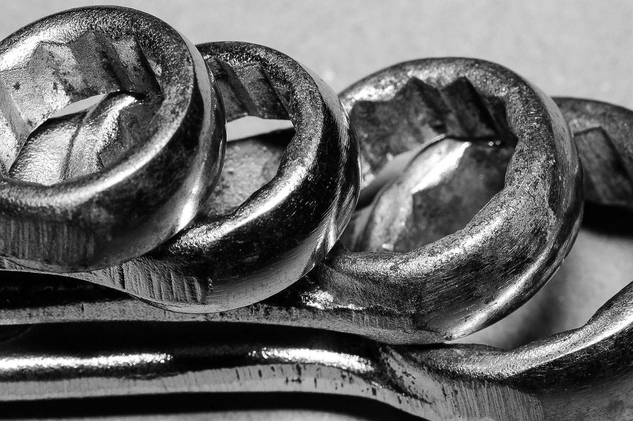 Una fotografía en blanco y negro de tres tuercas y una llave inglesa.