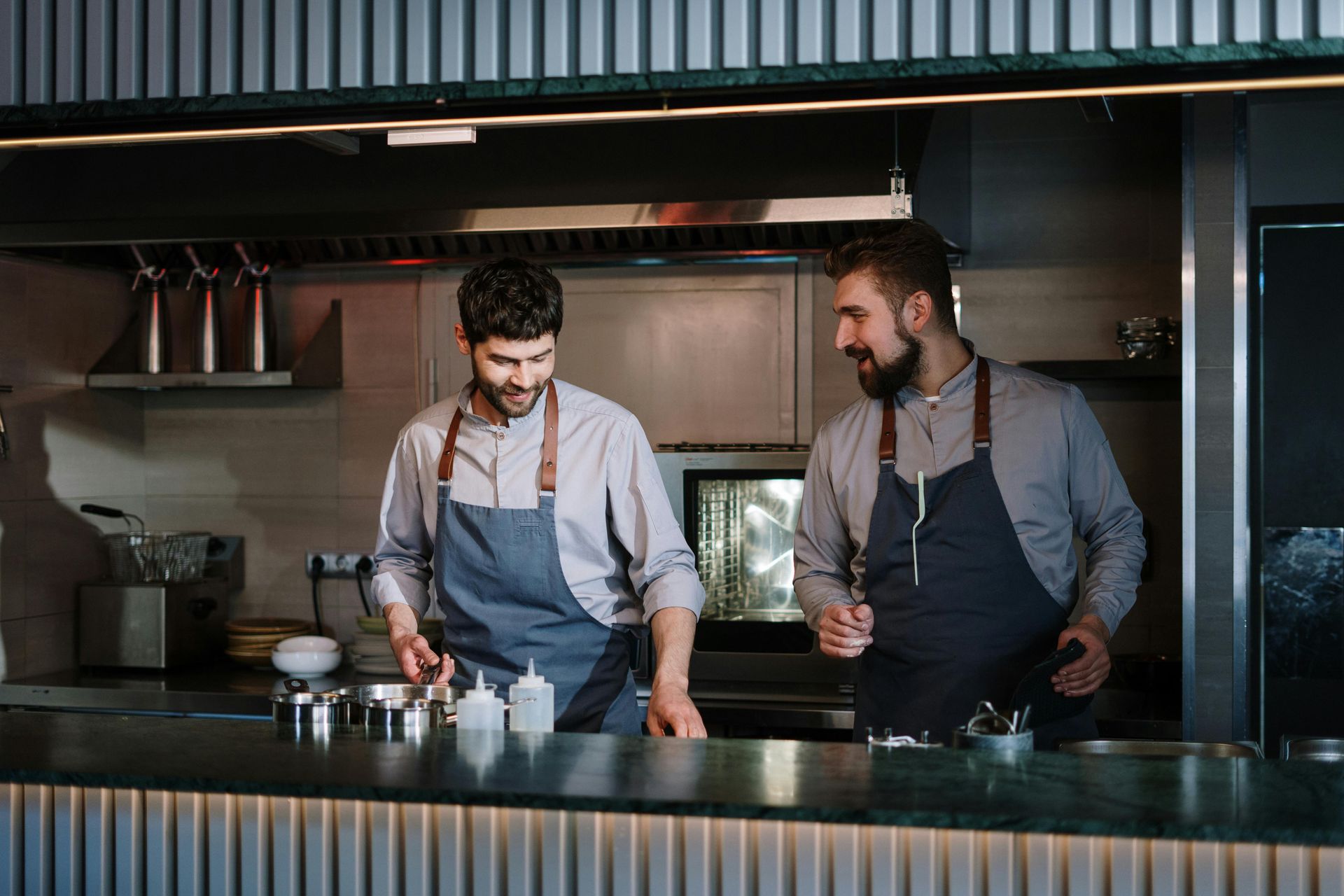 Dos hombres están de pie en una cocina hablando entre sí.