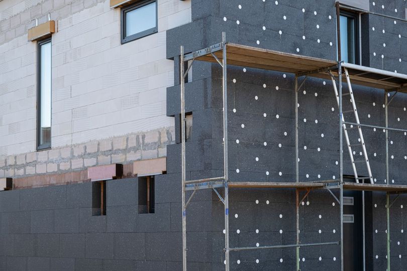 Extérieur de la maison en construction avec échafaudages et panneaux d'isolation foncés