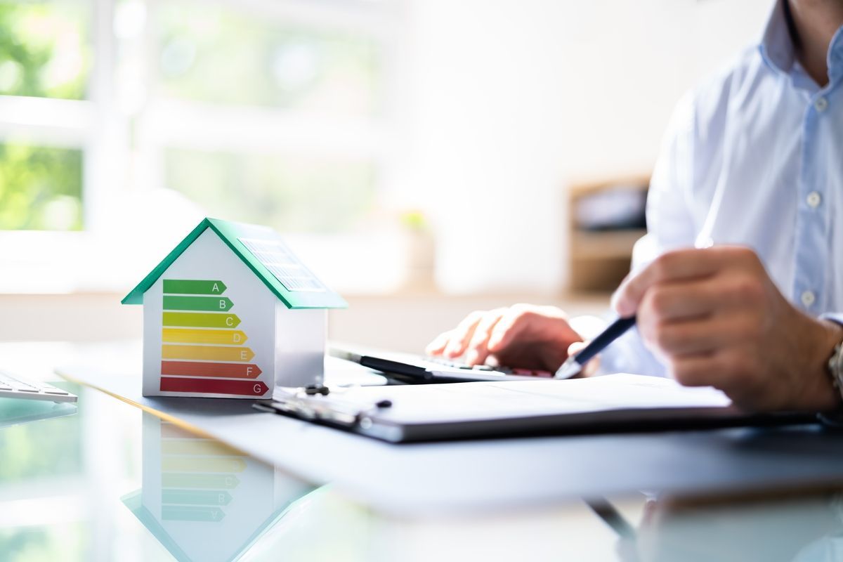 Fachada de edificio de apartamentos de color rojo y crema con múltiples ventanas, vista en ángulo contra un cielo azul.