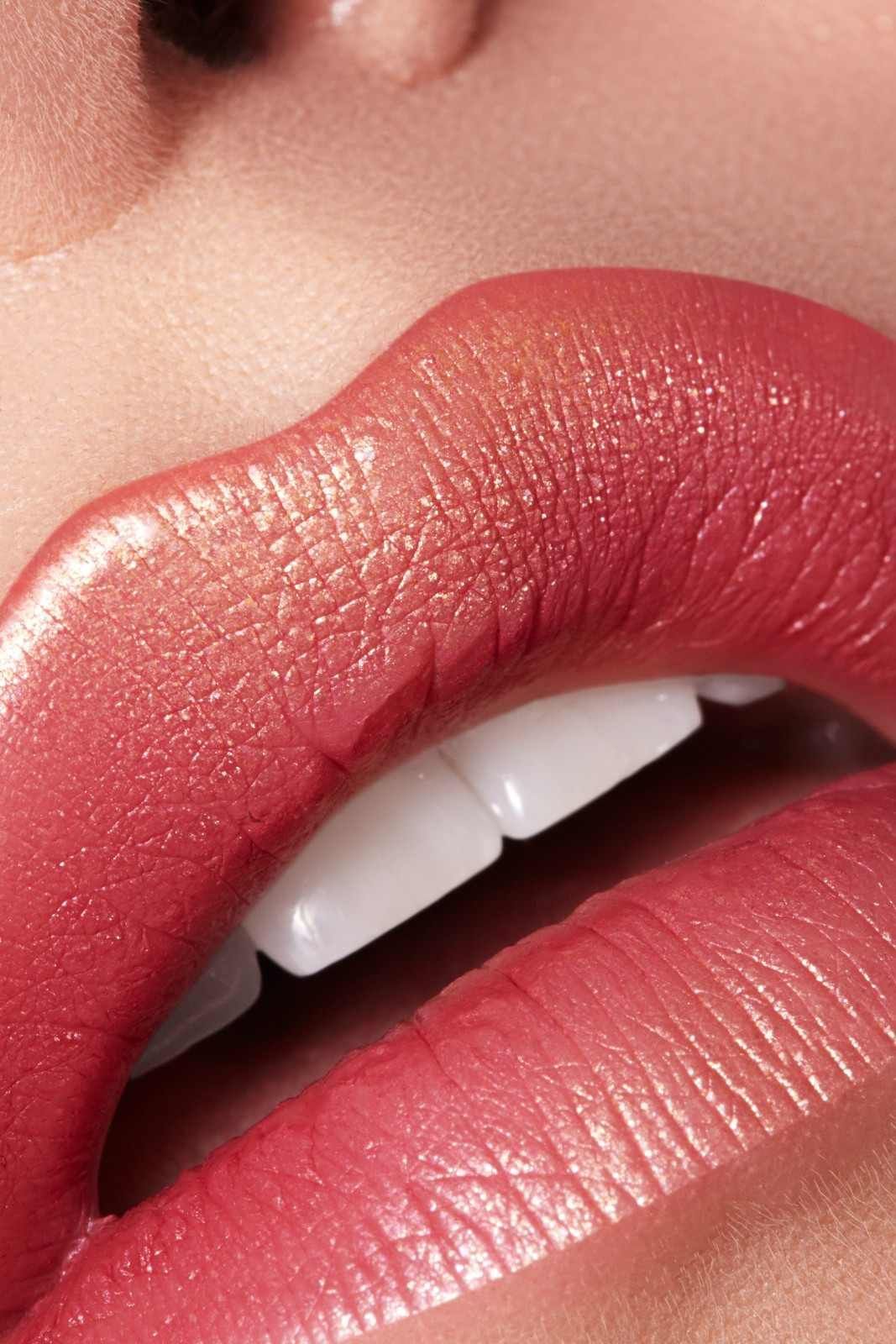 Primer plano de unos labios rosas brillantes, con los dientes blancos a la vista y la textura de la piel