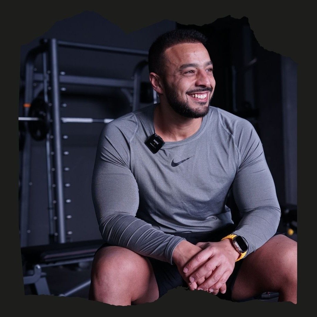 Un hombre que lleva una camiseta Nike está sentado en un gimnasio.