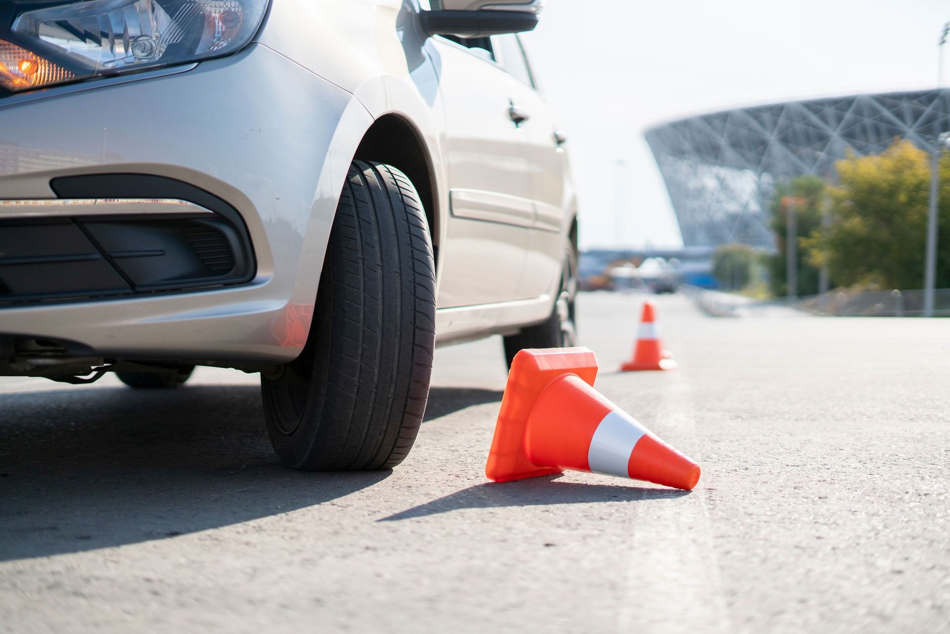 Silbernes Auto neben einem umgestürzten orangefarbenen Verkehrskegel auf einer Straße