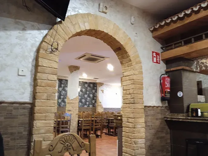 Un arco de ladrillo que conduce a un restaurante con mesas y sillas.