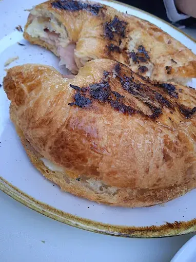 Un primer plano de un croissant en un plato con un mordisco quitado.
