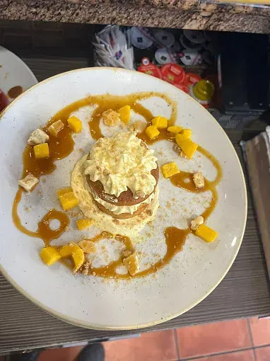 Un plato blanco cubierto con una pila de panqueques y salsa.