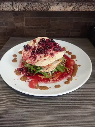 Un plato blanco con un sándwich y salsa sobre una mesa.