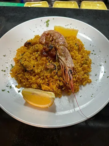 Un plato blanco cubierto con arroz, camarones y una rodaja de limón.
