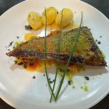 Un plato blanco cubierto con un trozo de carne y patatas.
