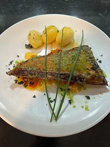 Un plato blanco cubierto con un trozo de carne y patatas.