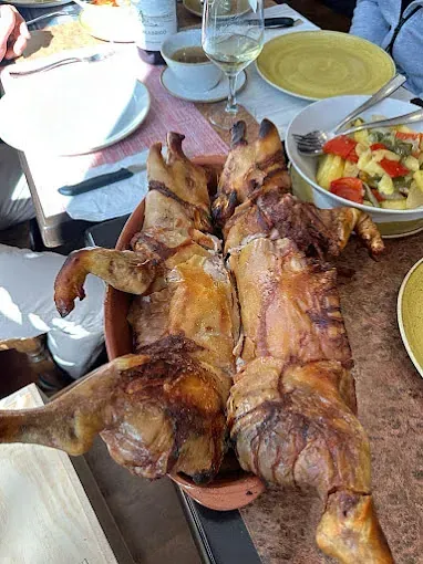 Un cerdo asado está sentado en una mesa al lado de un plato de verduras.